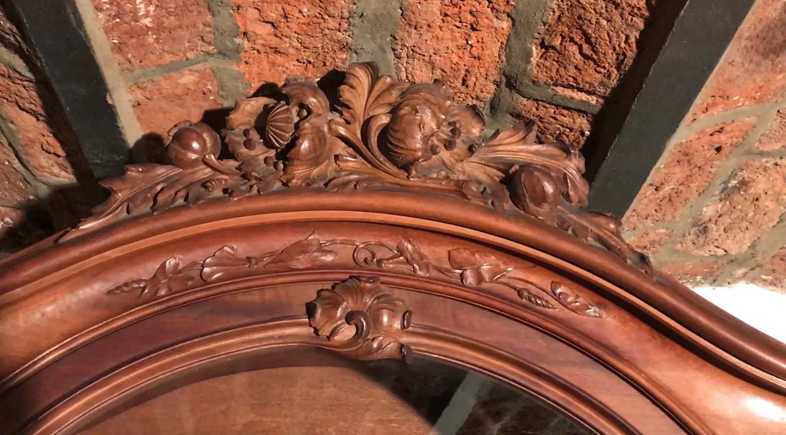 antique display cabinet with intricate carvings and brick background
