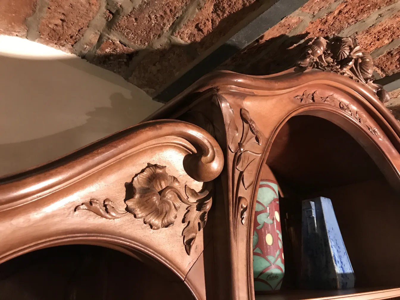 Detaillierte antike Vitrine mit floralen Akzenten, die eine gemütliche Umgebung dekoriert.