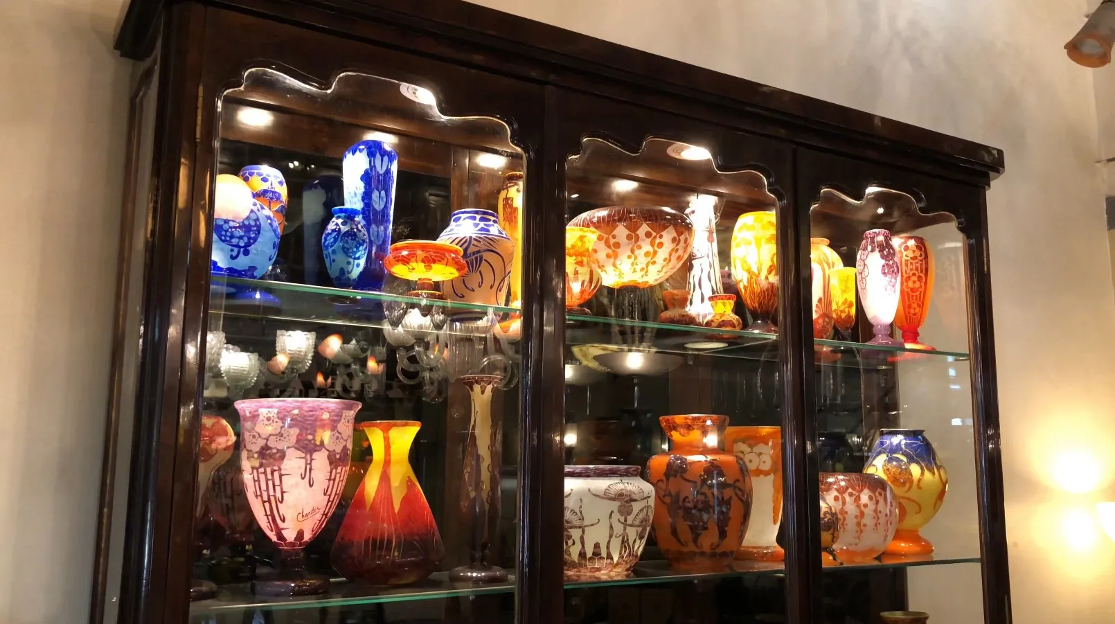 Vitrine ancienne présentant des vases colorés