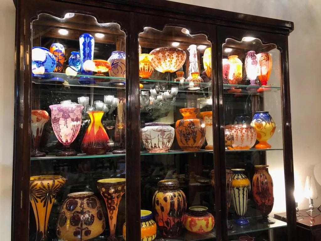 Vitrine antiga iluminada com vasos coloridos e potes