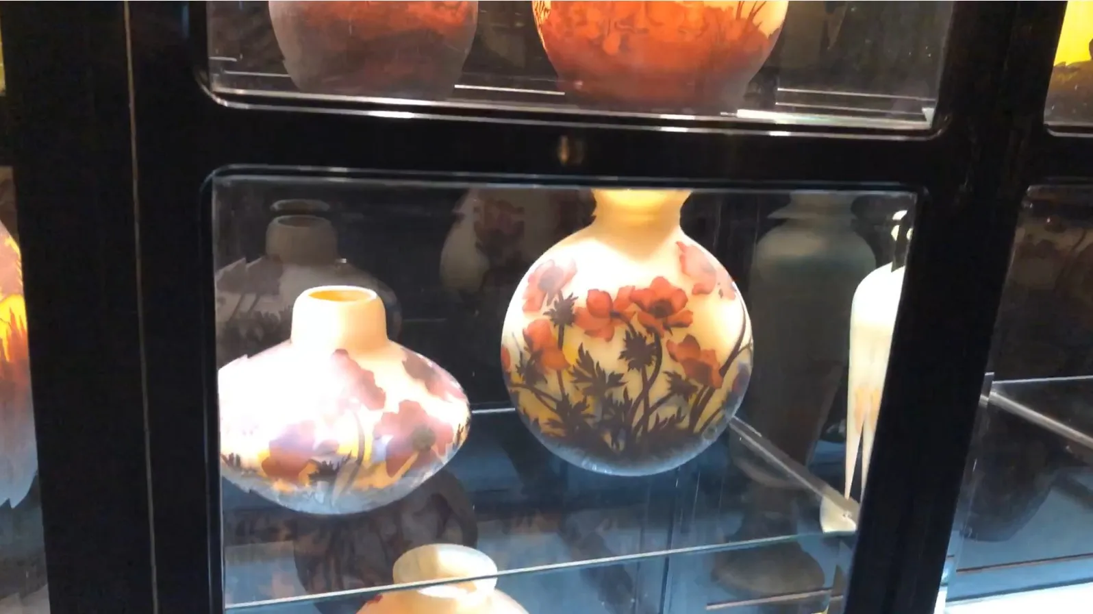 古董展示柜内展示多种装饰性瓶子，带有丰富的花卉装饰。