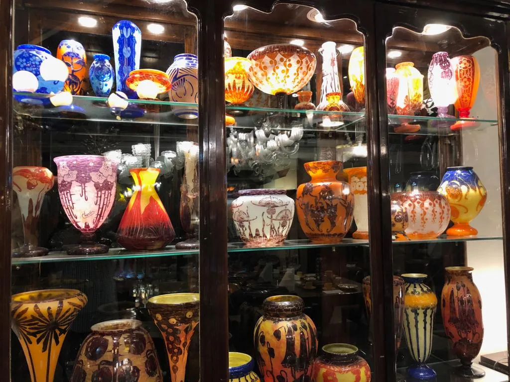 Antike Vitrine mit verschiedenen bunten Dekorvasen in einer gemütlichen Umgebung.