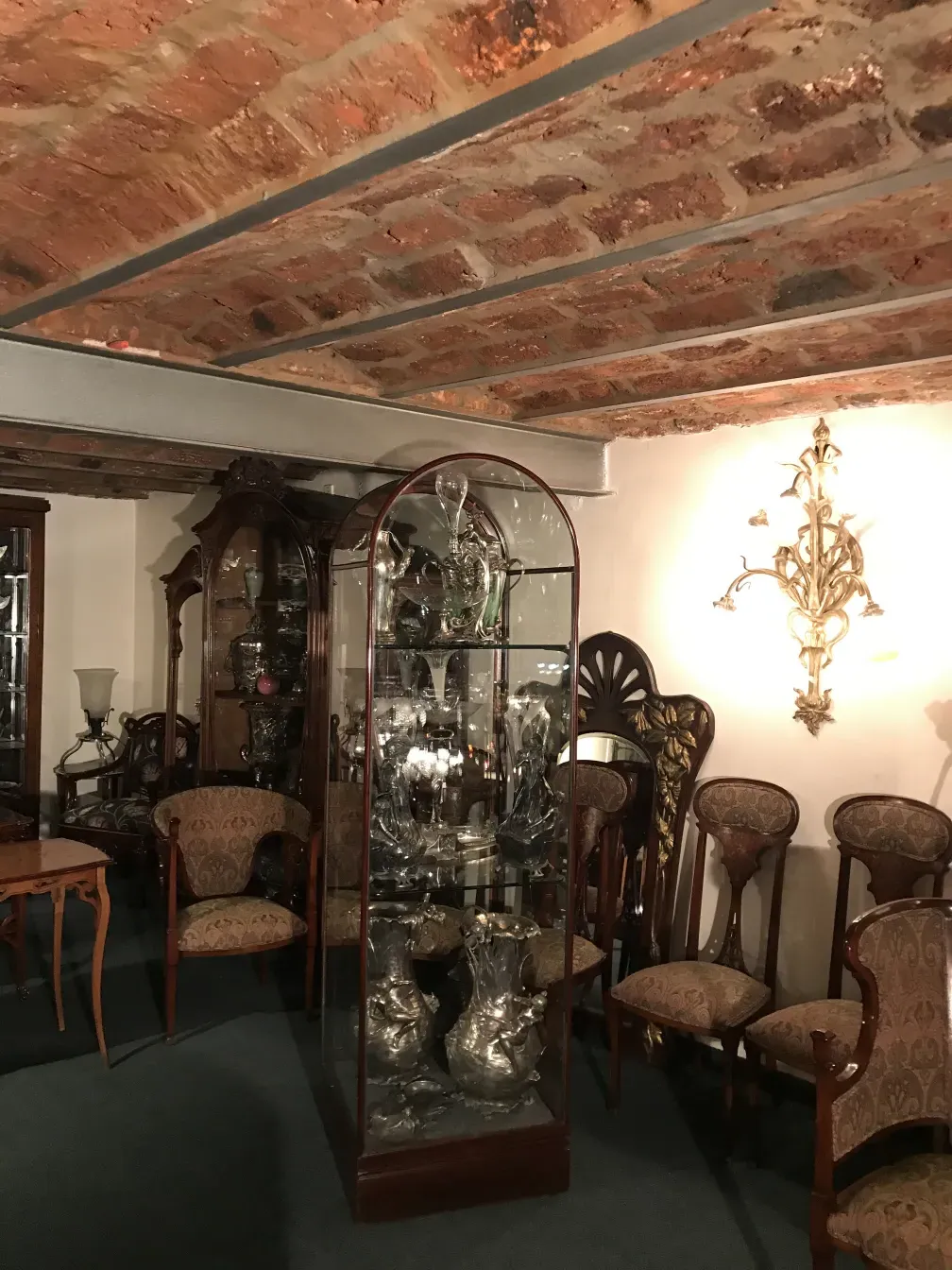 Antike Vitrine mit dekorativen Sammlerstücken, vintage Möbel im Hintergrund.