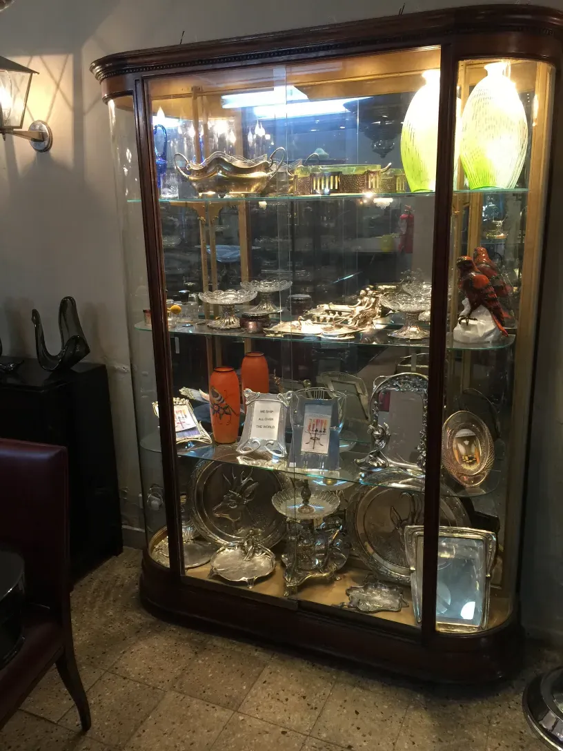 Antique display cabinet showcasing decorative and collectible items in a cozy setting.
