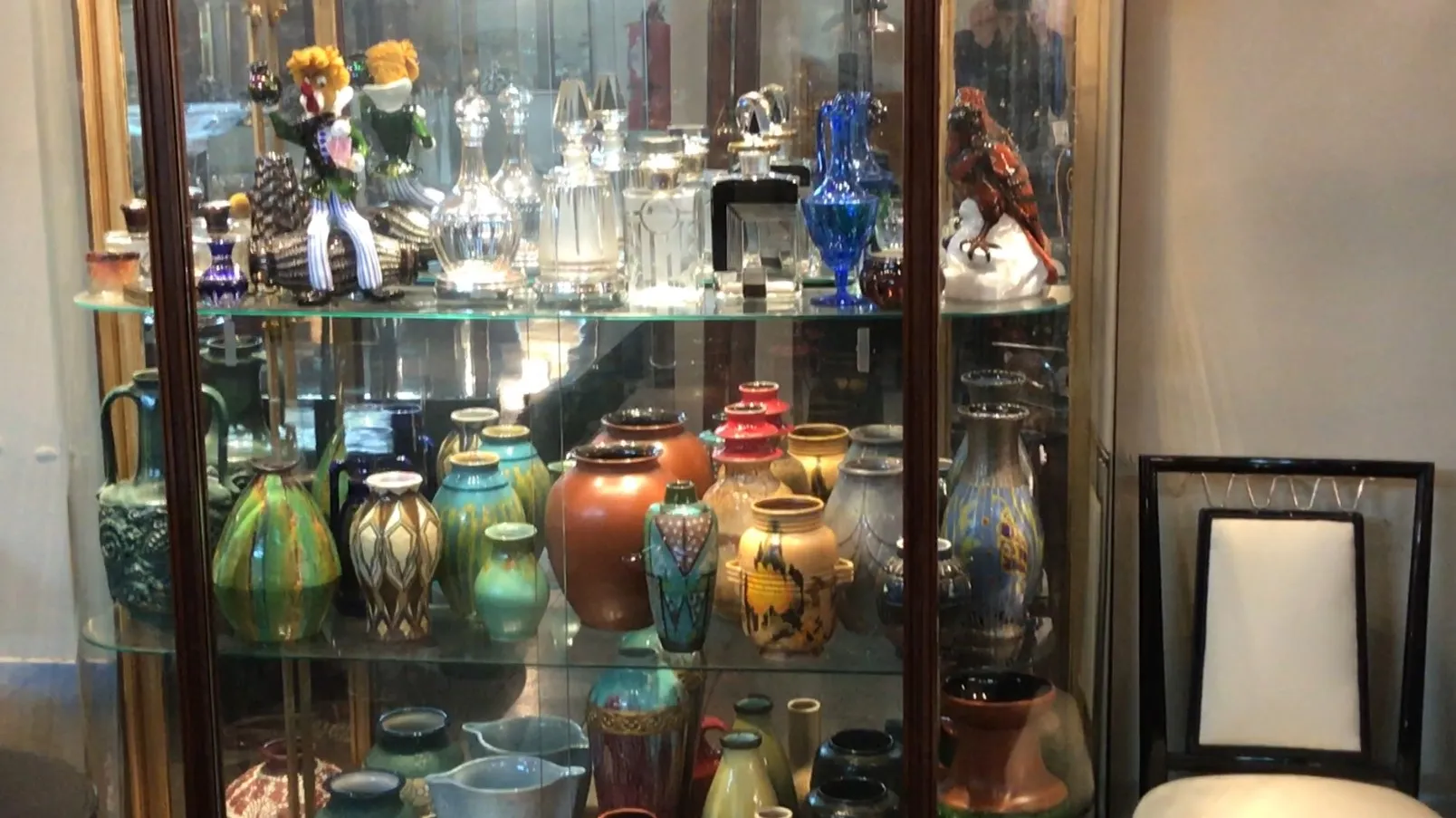 Vitrina antigua con objetos decorativos variados, coloridos.