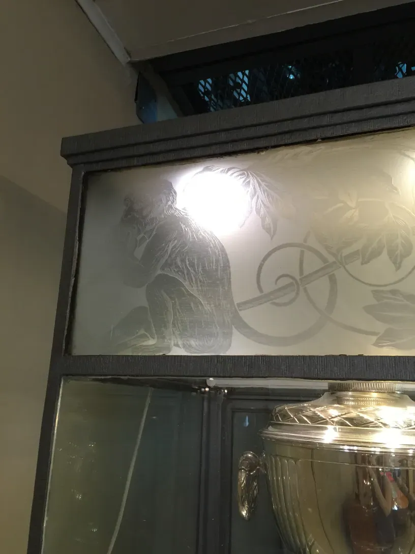 Vitrine antique avec des détails décoratifs en haut et un fond clair