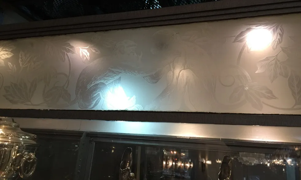 Antike Vitrine mit Affenmotiv und gravierten Blättern.