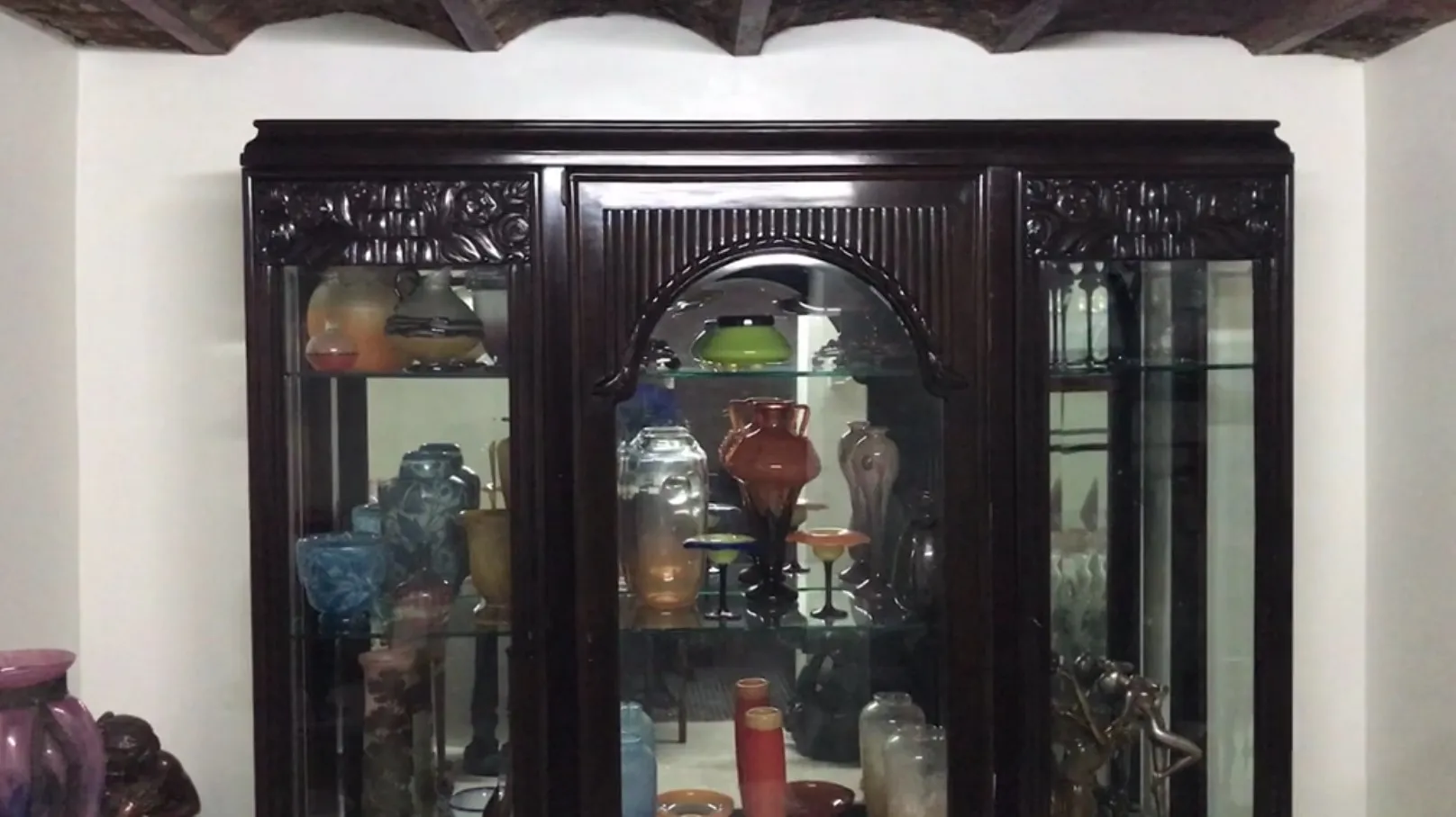 Antique display cabinet filled with decorative items in a cozy setting.