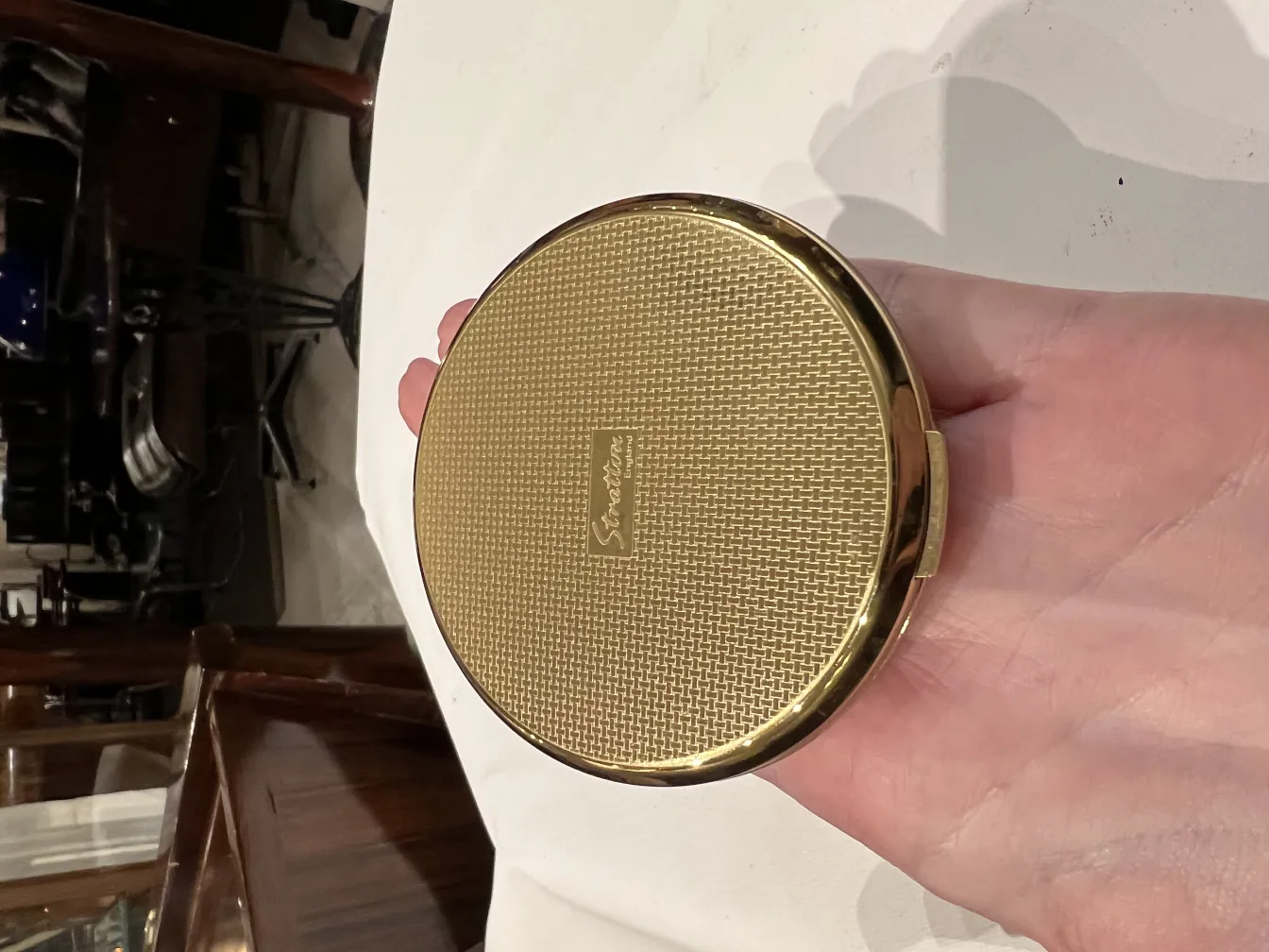 polvera dorée antique avec texture et design élégant dans la main