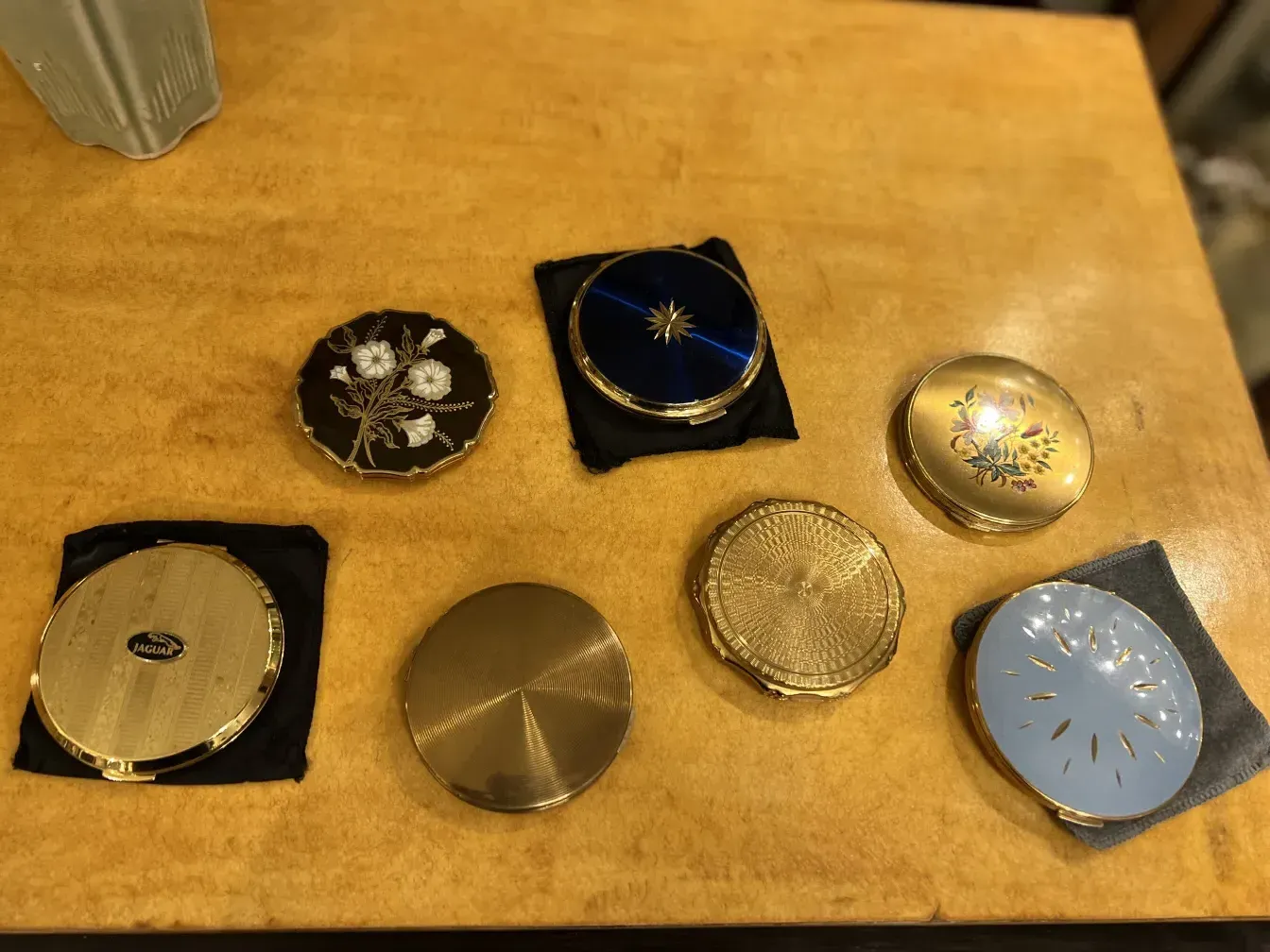 Polvera antigua jaguar stratton con diseño floral sobre mesa de madera