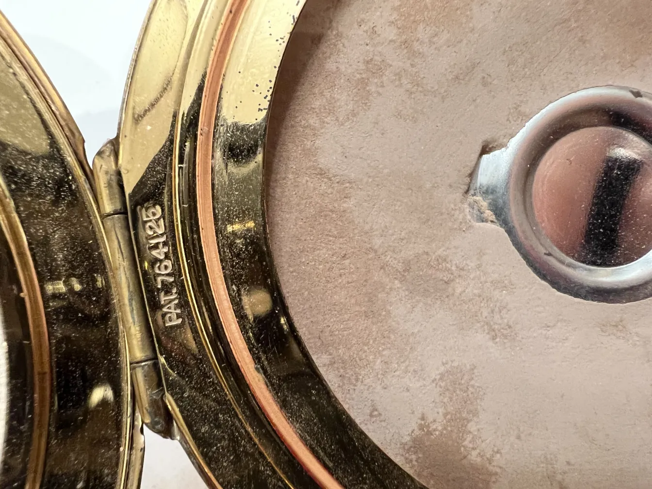 Polvera antica con finitura dorata e specchio interno, ambiente elegante.