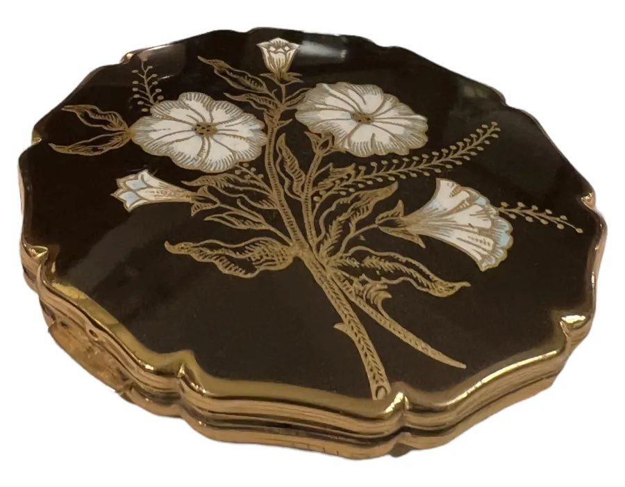 polvera antigua con un diseño floral en la tapa