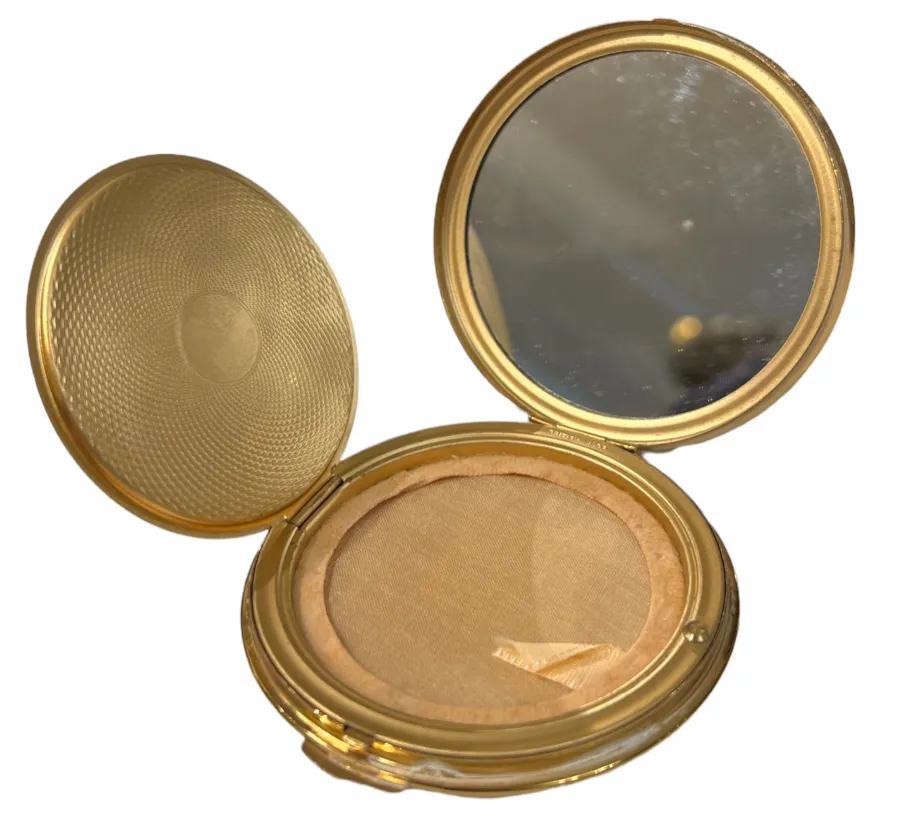 compact antico con specchio oro e sfondo chiaro