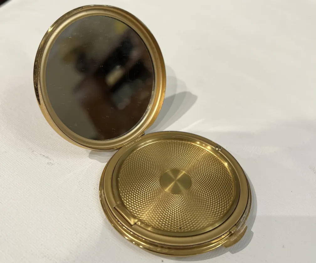 Polverina antica con un design dorato e uno specchio interno.