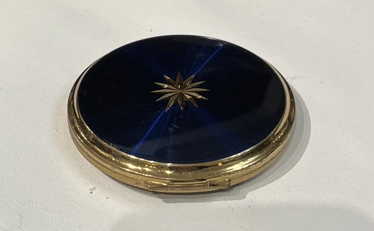 polvera antiga com tampa azul e design floral dourado