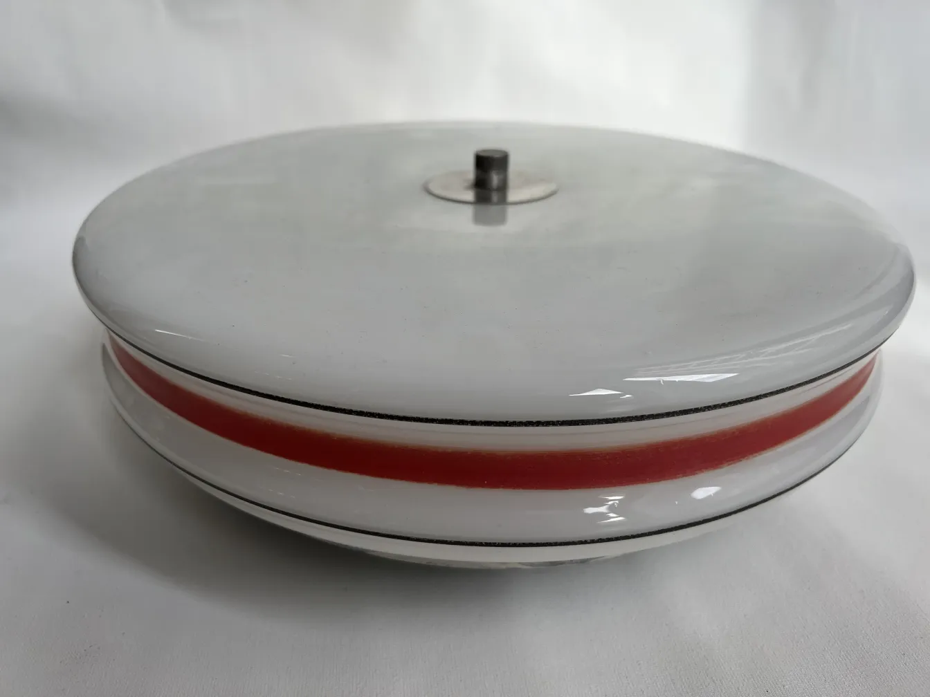 plafon antiguo de forma redonda con detalles rojos y base metálica en un fondo blanco