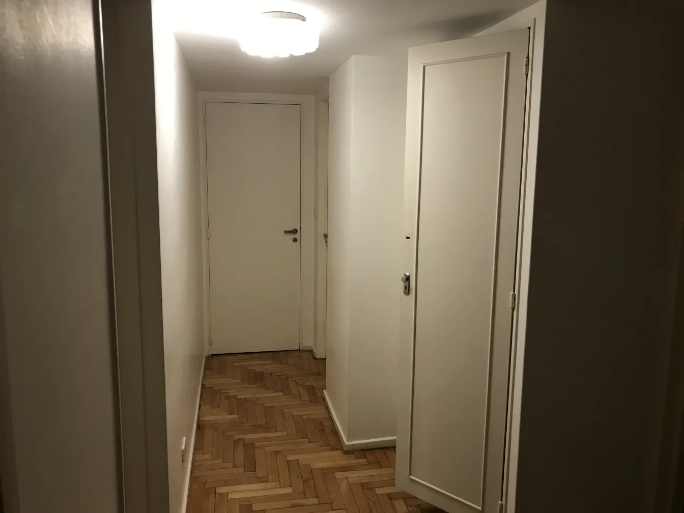 plafonnier ancien éclairant un couloir aux murs clairs