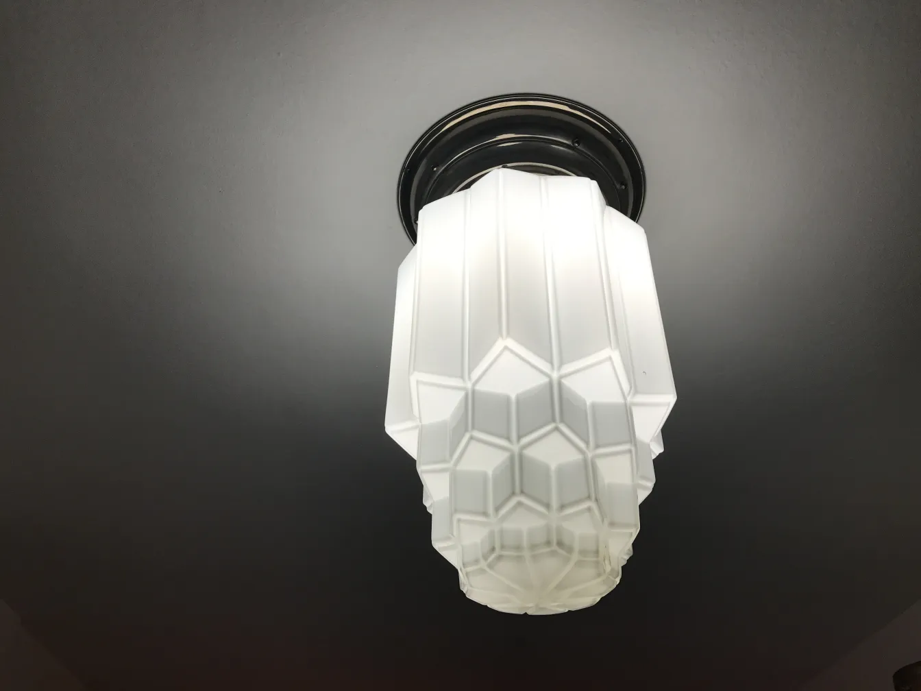 Duas luzes de teto antigas com design decorativo cúbico, instaladas em um teto escuro.