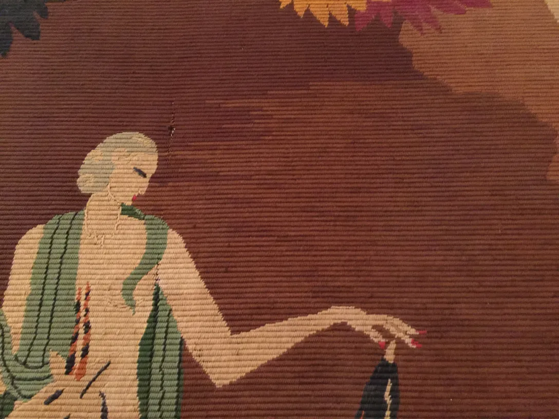 Tapisserie ancienne décorative avec figure féminine dans des tons chauds et des accents floraux