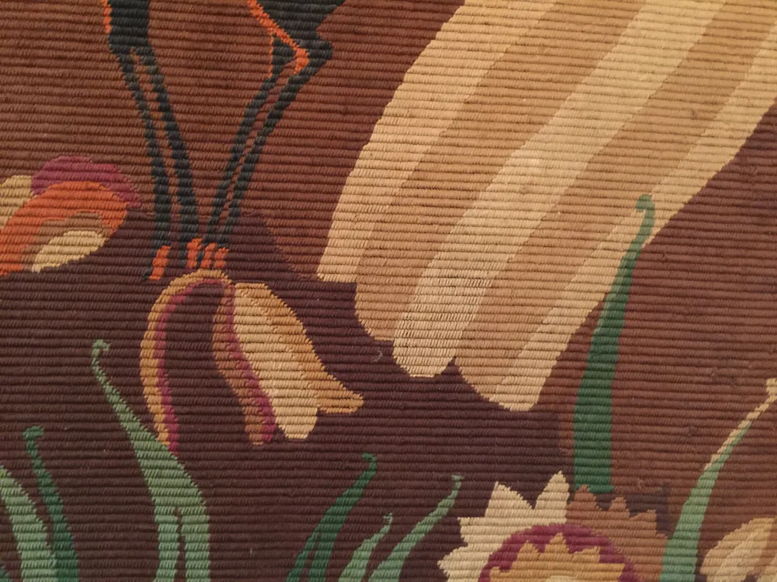 antiker Wandteppich mit warmen Farben und lebhaften Blumenmustern