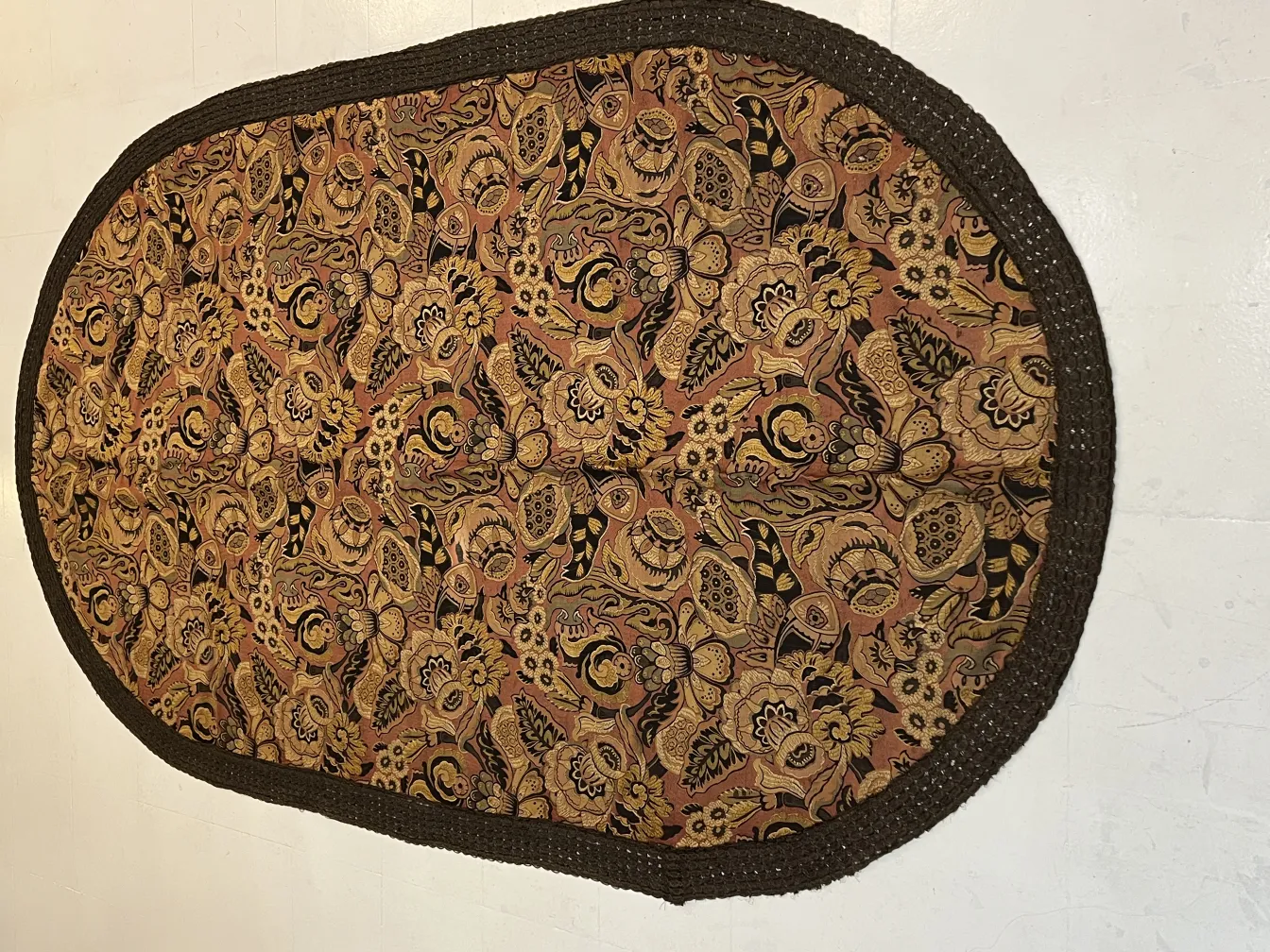 antique oval tablecloth featuring colorful floral patterns on a brown background