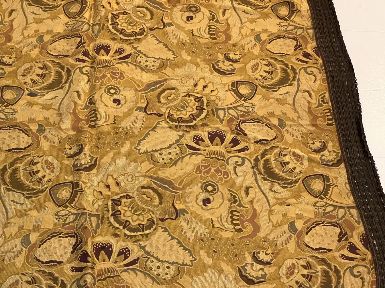 antike Tischdecke mit lebhaften Blumenmustern in warmen Tönen, die eine gemütliche Atmosphäre auf dem Tisch schafft.