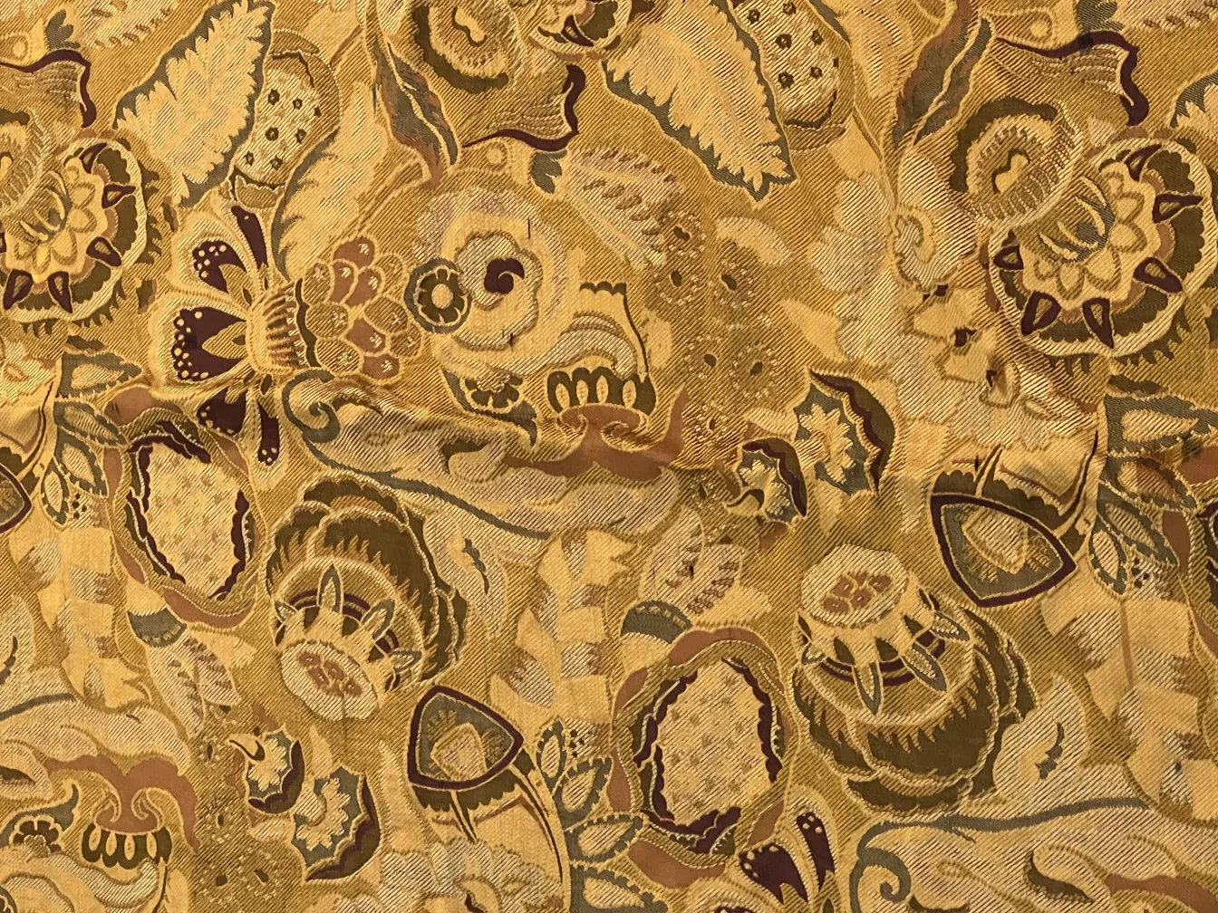 Mantel antiguo con flores en dorado y tonos burdeos, fondo texturizado.