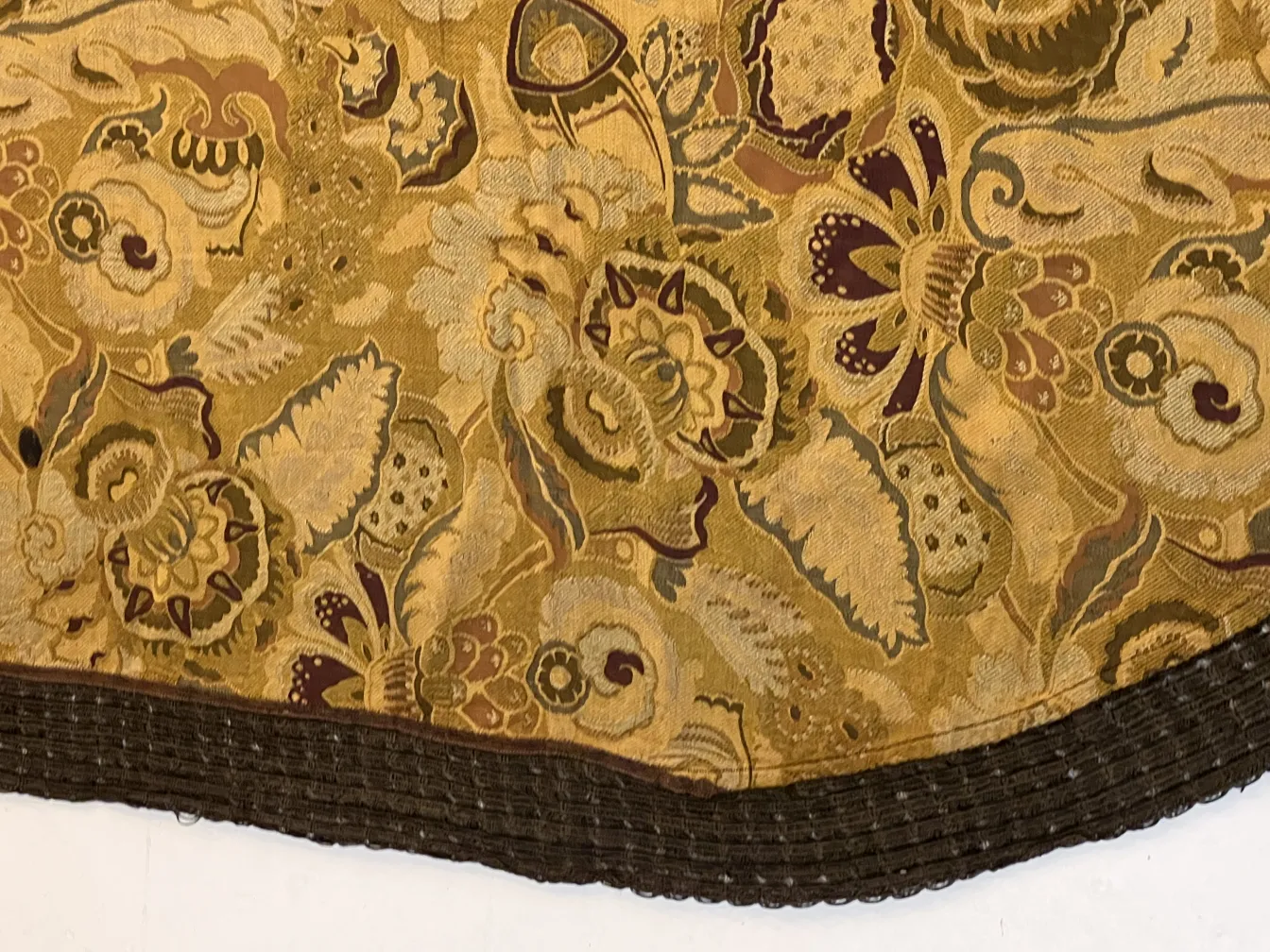 Antique tablecloth with colorful floral print and contrasting border, laid on a white surface.