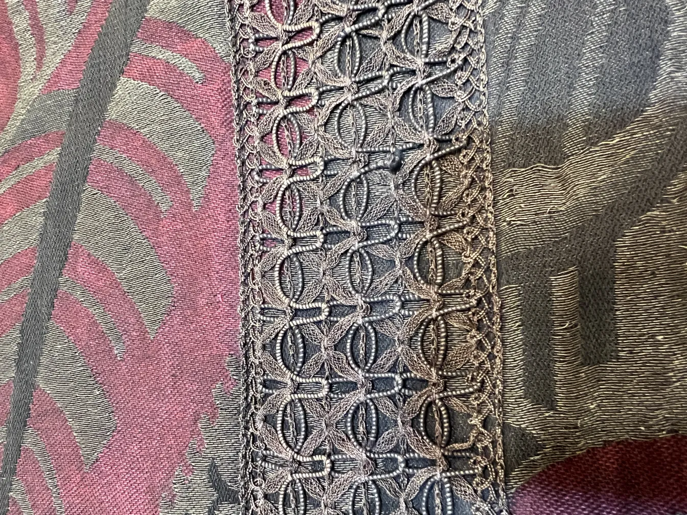 Detail der antiken Tischdecke mit dekorativen Rändern, bunter Hintergrund