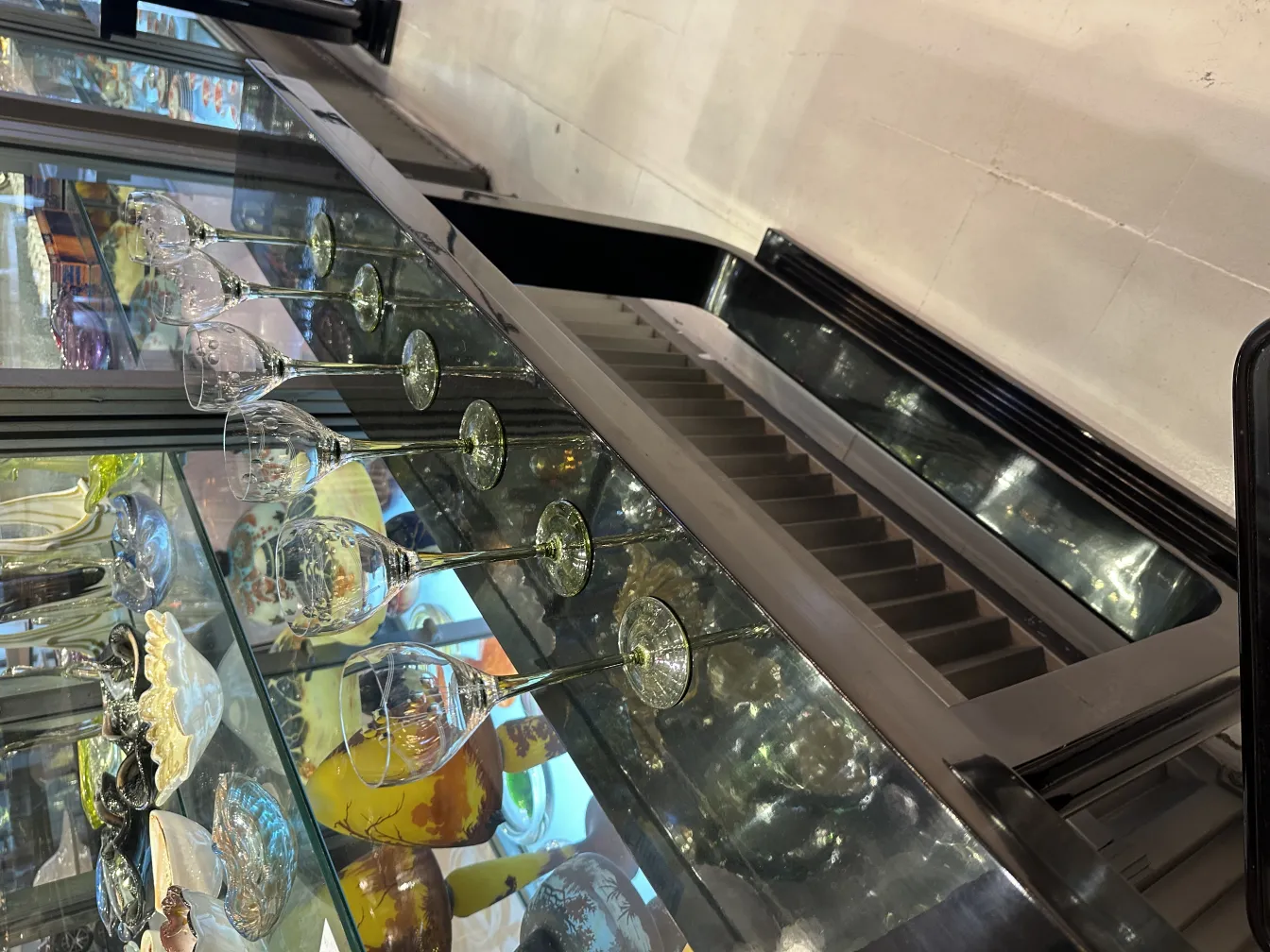 six antique glasses displayed on a glass shelf