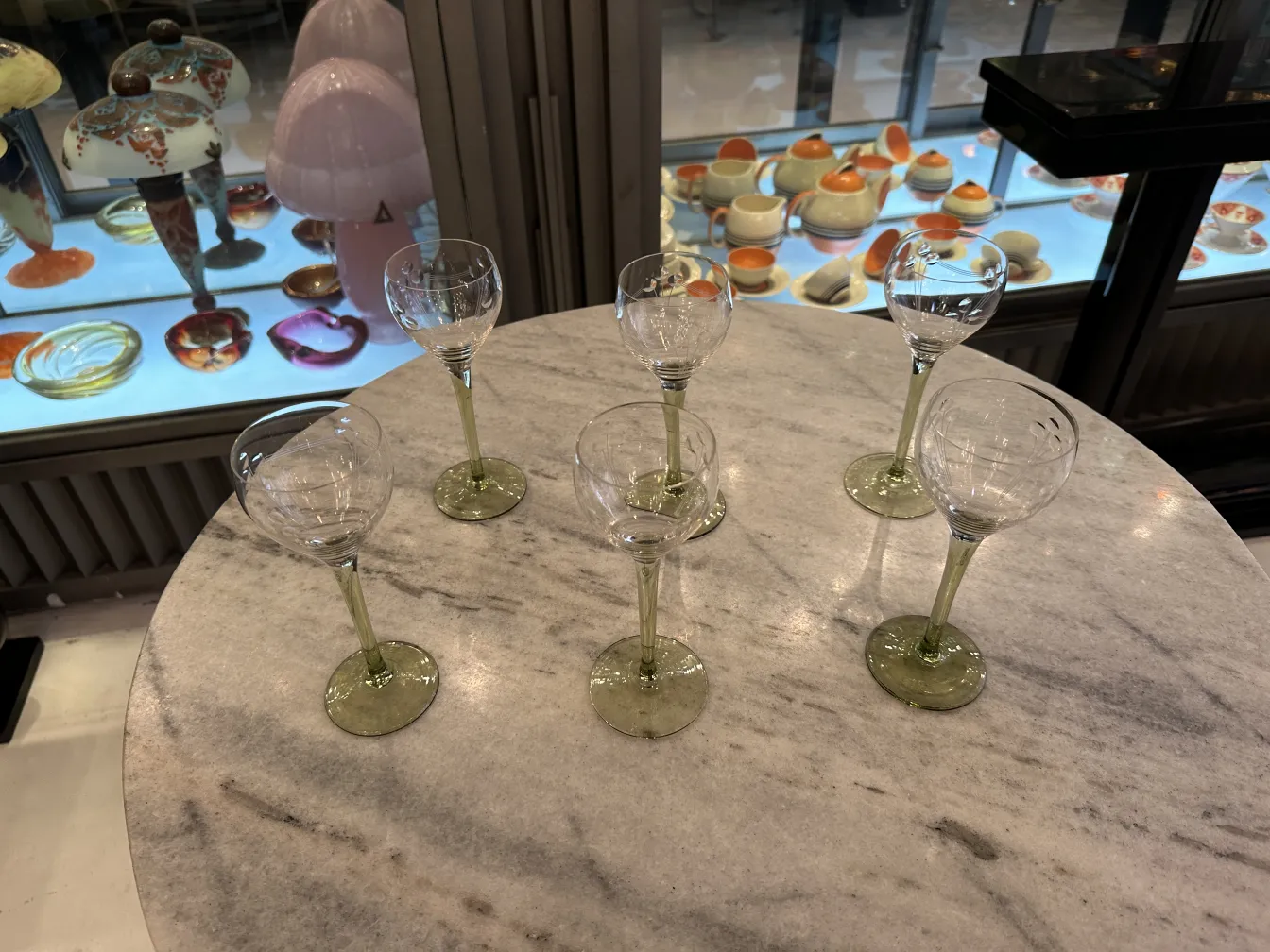 Conjunto de 6 copas antiguas de cristal en una mesa de mármol.