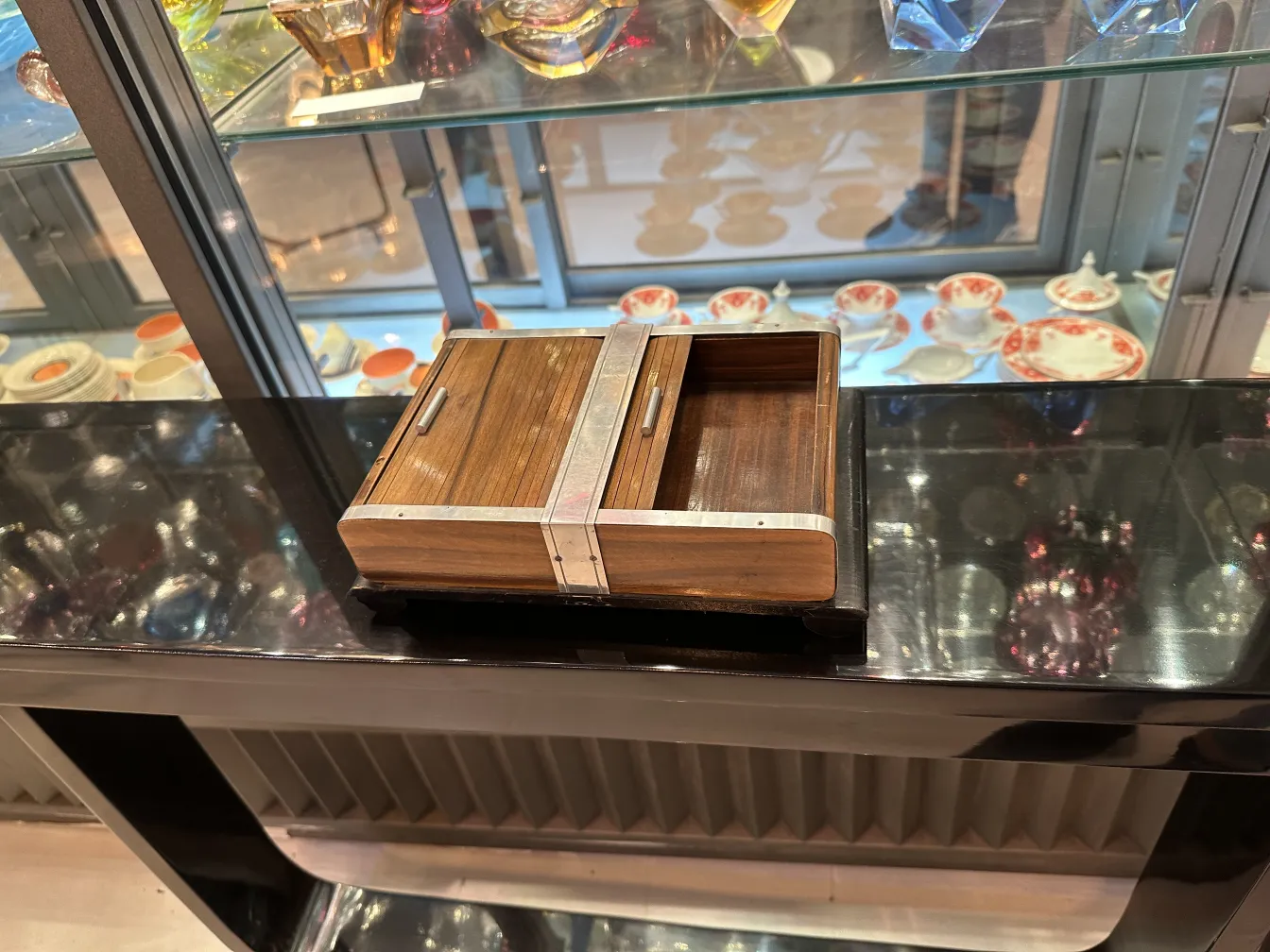 Boîte ancienne à bijoux avec des accents en métal et des compartiments intérieurs, exposée sur une étagère sombre.