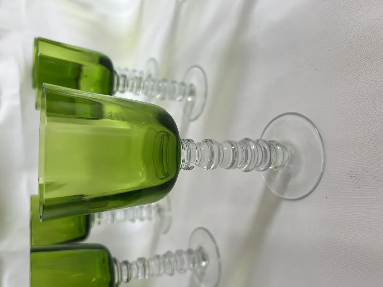 Set of 12 antique Querandi glasses in green. Elegant design on a white background.
