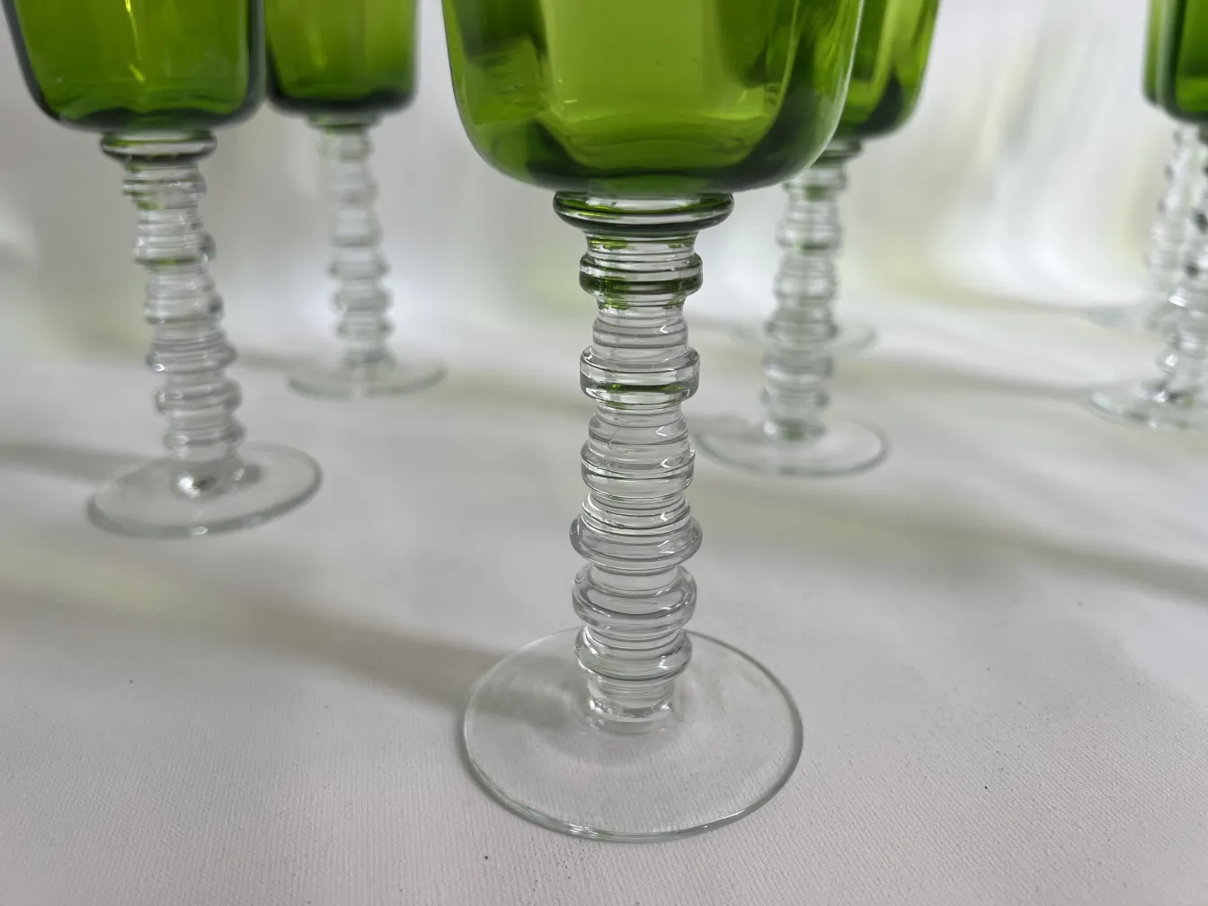 dodici bicchieri antichi con base in vetro trasparente e design elegante