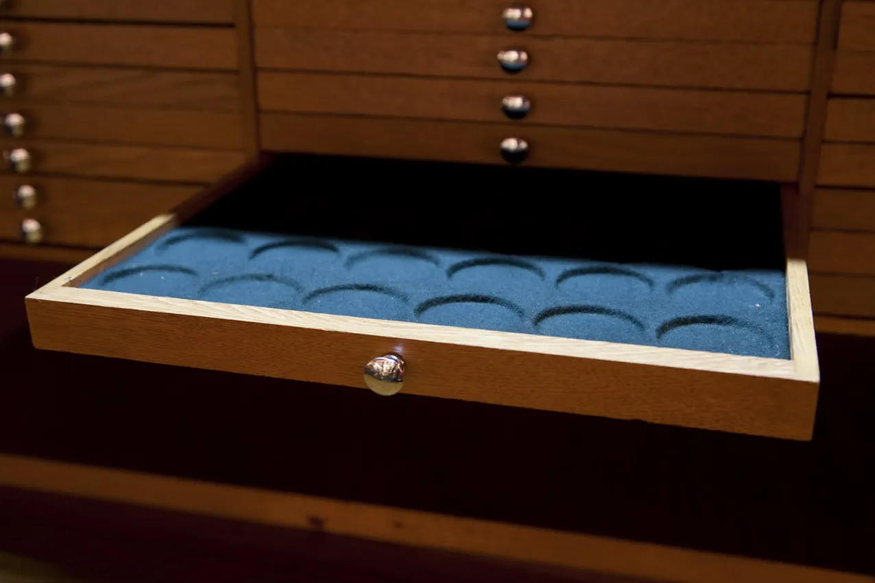 Meuble ancien avec compartiments pour pièces de monnaie, fond bleu.