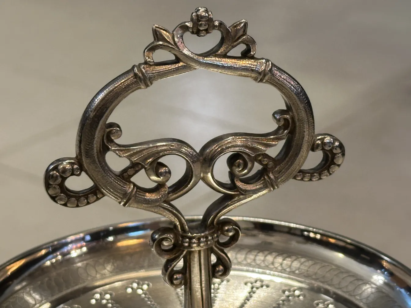 Plat à pâtisserie ancien avec un design décoratif en haut et une poignée élaborée, parfait pour présenter des desserts