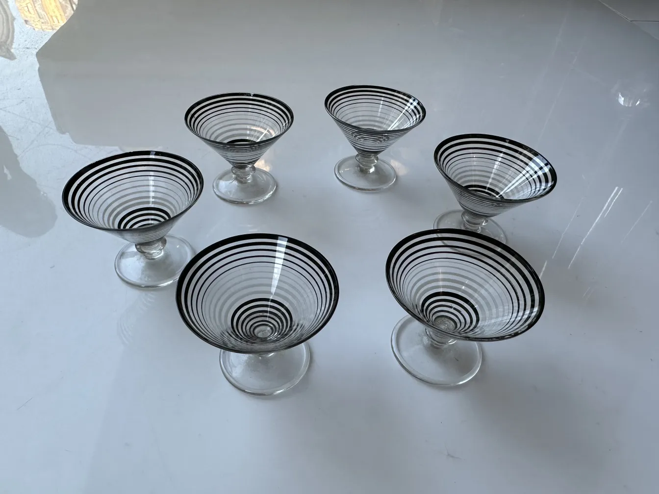 licoreira antiga e seis taças com desenhos espiralados sobre fundo branco