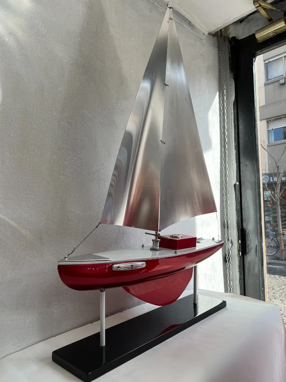 Antique model of designer's ship, red and silver, displayed.