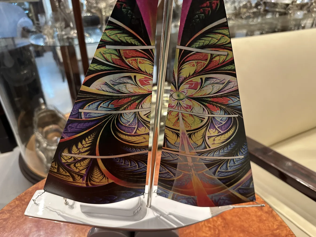 Barco antiguo con velas coloridas diseñado por Marcelo Peña en un entorno elegante.