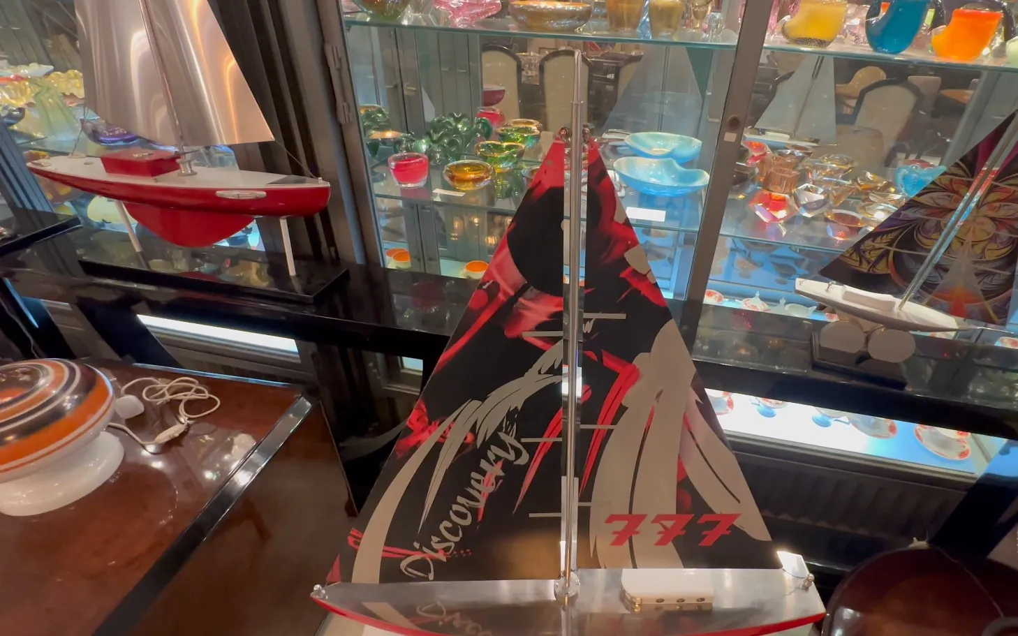 Modèle de bateau du designer avec des voiles rouges et un design moderne, dans un cadre ancien.