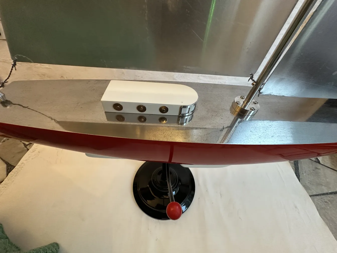 Modello antico di una barca del designer con finitura rossa e dettagli sofisticati, presentato in un ambiente neutro.