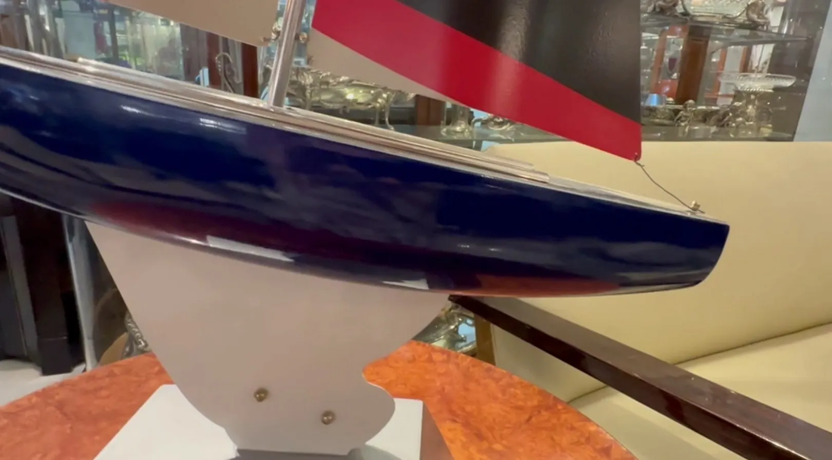 Modello di barca antica del designer Marcelo Peña, colori blu e rosso, in un ambiente elegante.