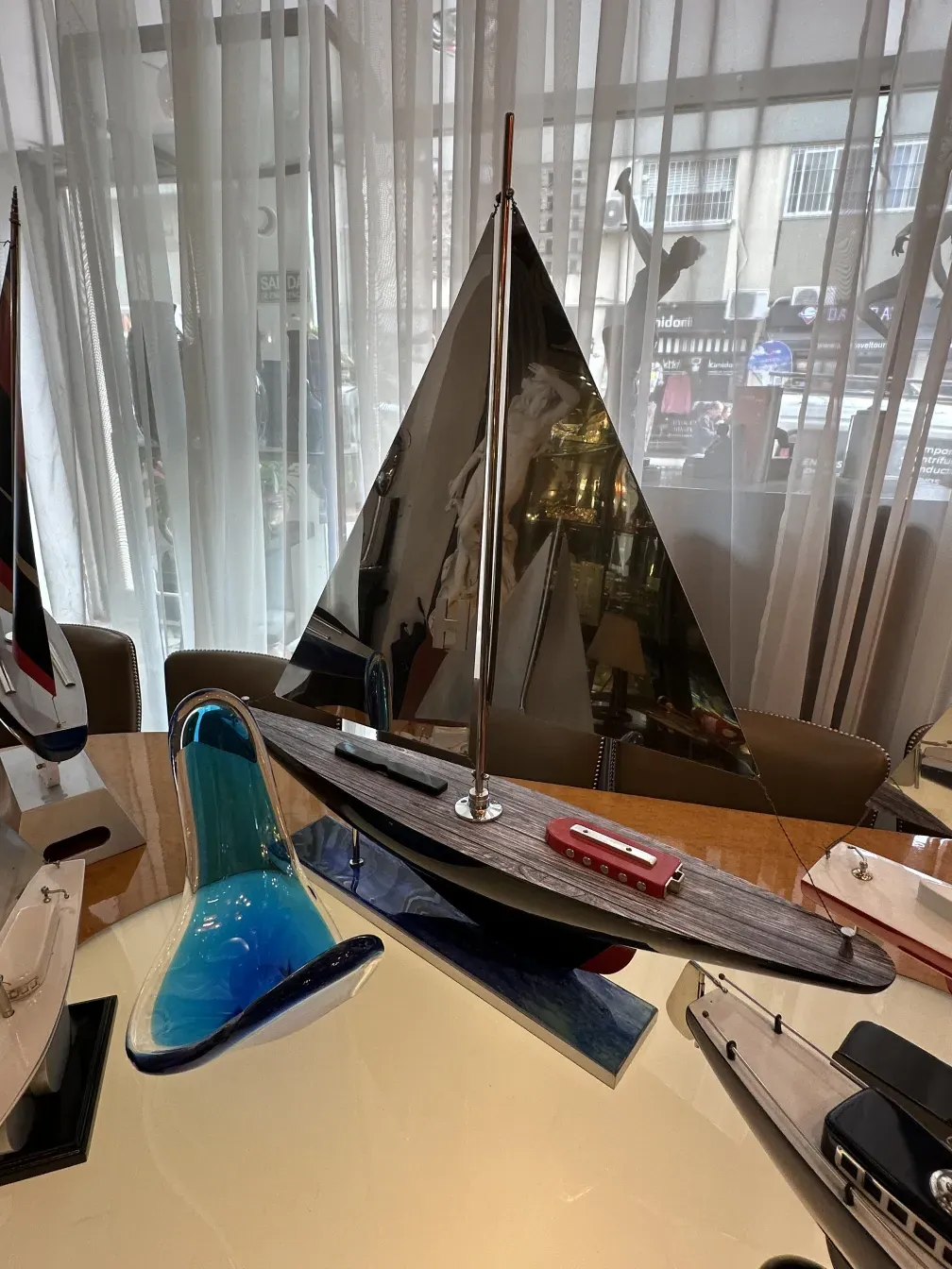 model of a ship with a metallic sail and colorful base, decorative pieces around