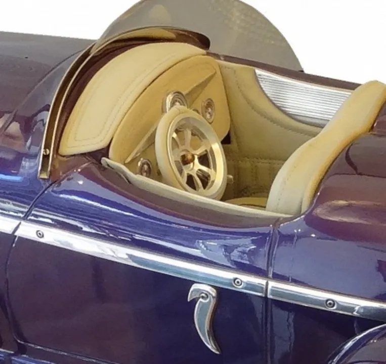 Внутренний вид античного автомобиля дизайнера Марсело Пенья с кремовыми деталями и серебряным рулем.