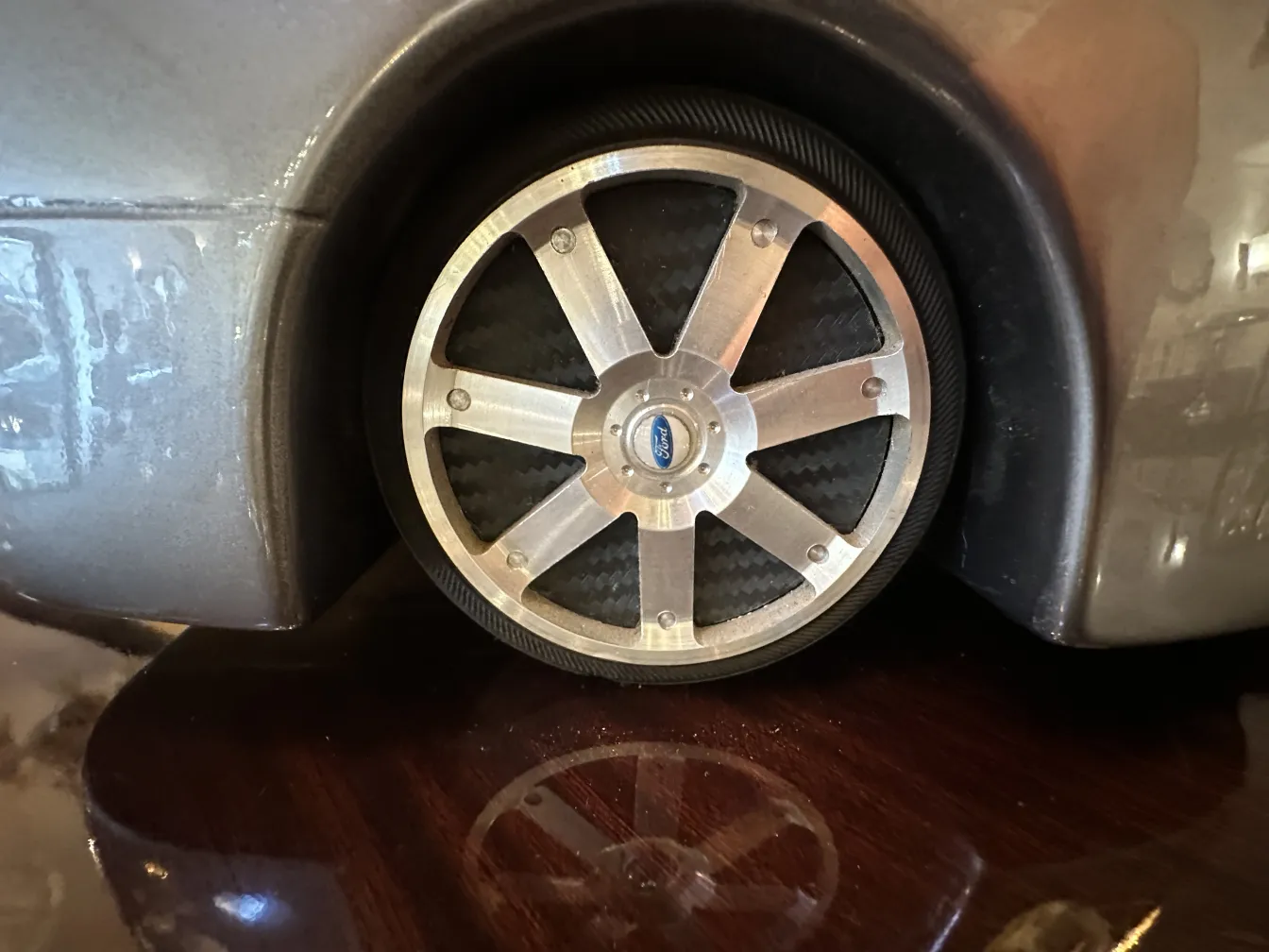 Close-up view of an antique designer car with modern wheels, reflecting its surroundings.