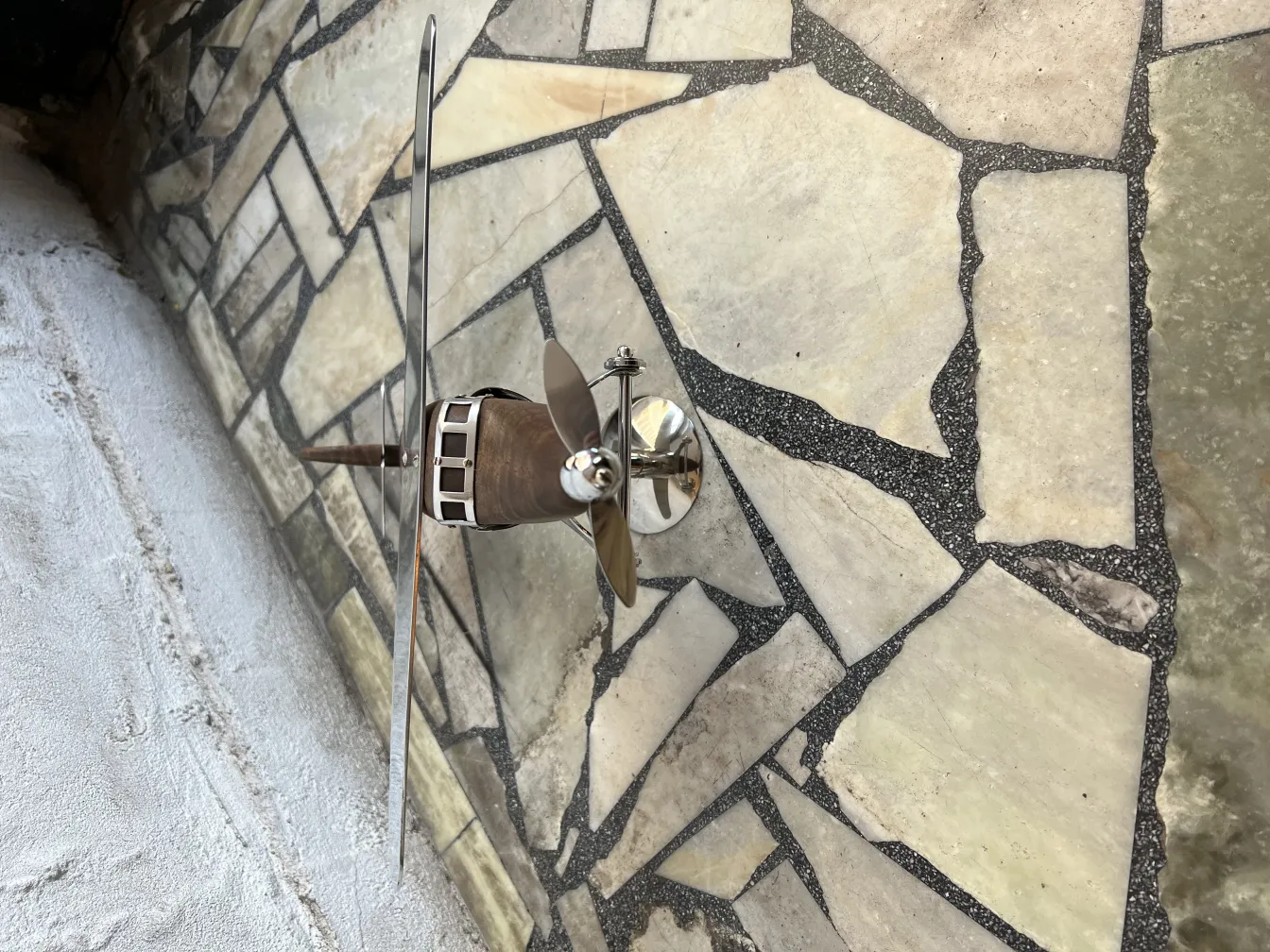 Modelo de avião antigo do designer Marcelo Peña sobre um fundo de pedras.