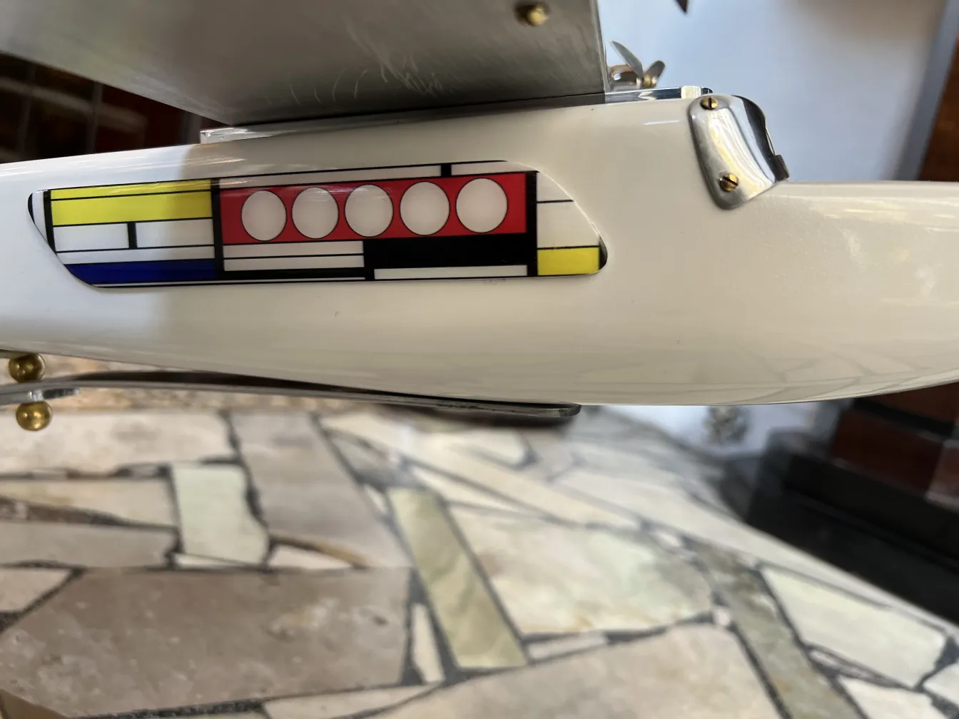 Detail of antique aircraft by designer Marcelo Peña with vibrant colors on a stone background.