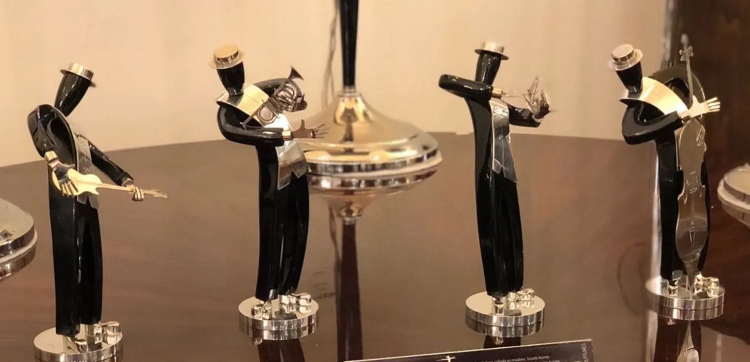 Esculturas antigas de uma banda de música, figura com guitarra e outros instrumentos, ambiente elegante.