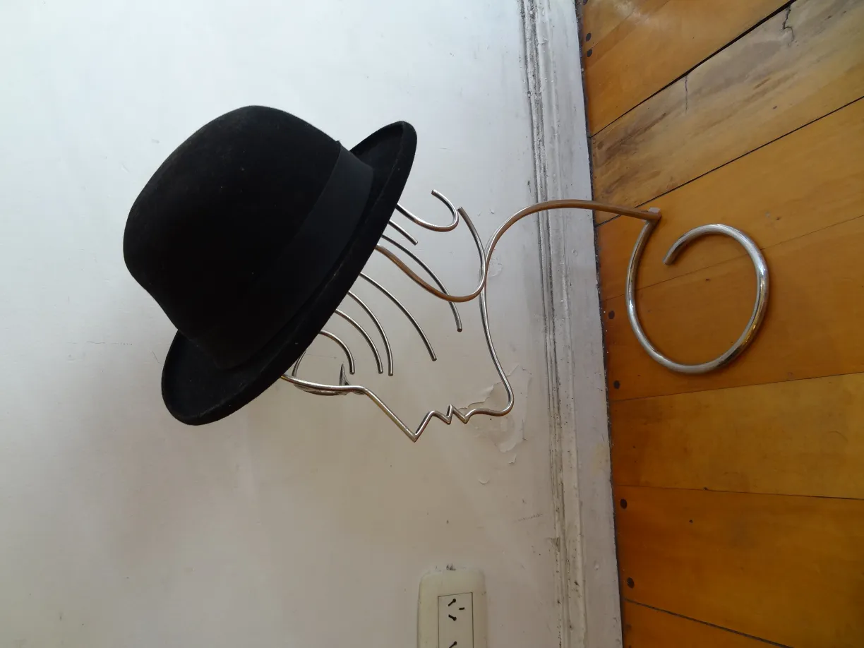 sculpture antique avec visage et chapeau noir sur le mur