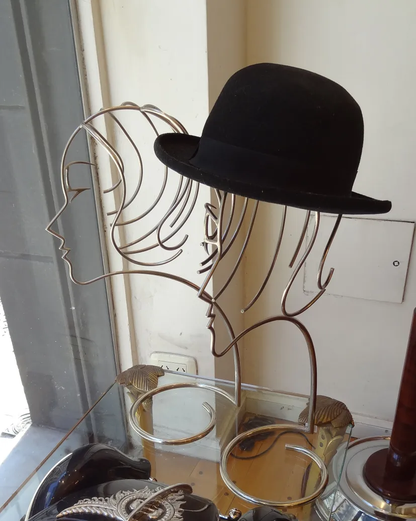 scultura antica con sagome di teste e cappello nero